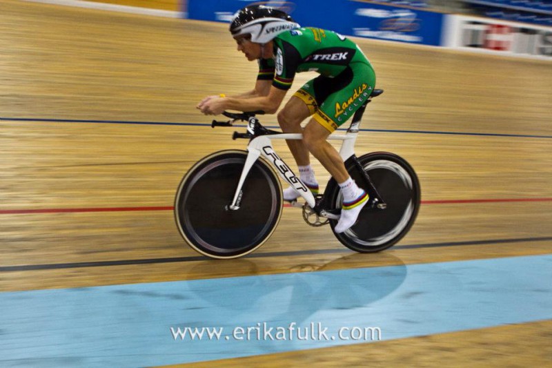 A cyclist racing on a track in a gym.